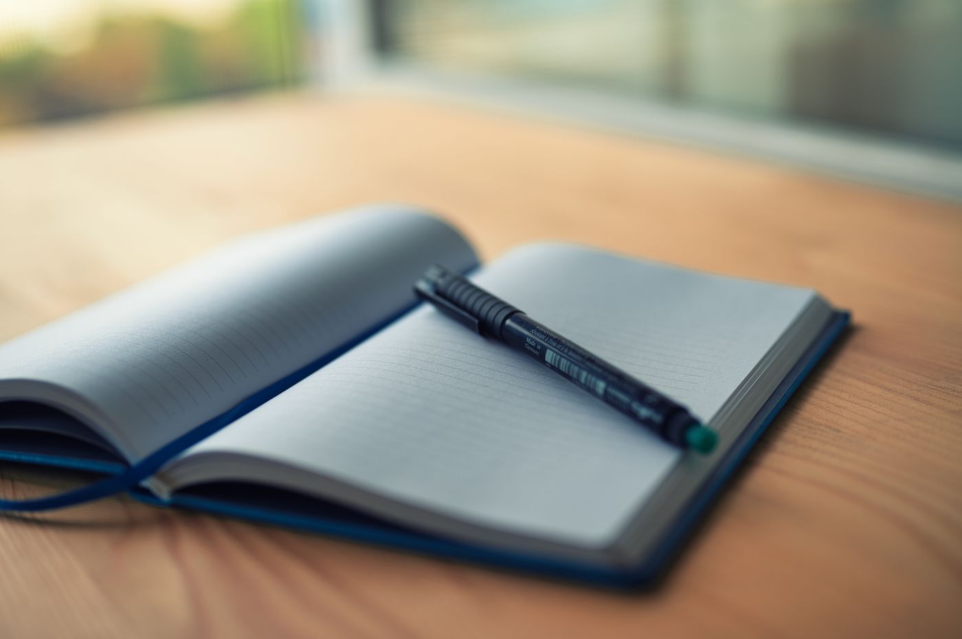 An open notebook and pen on a wood tabletop.
