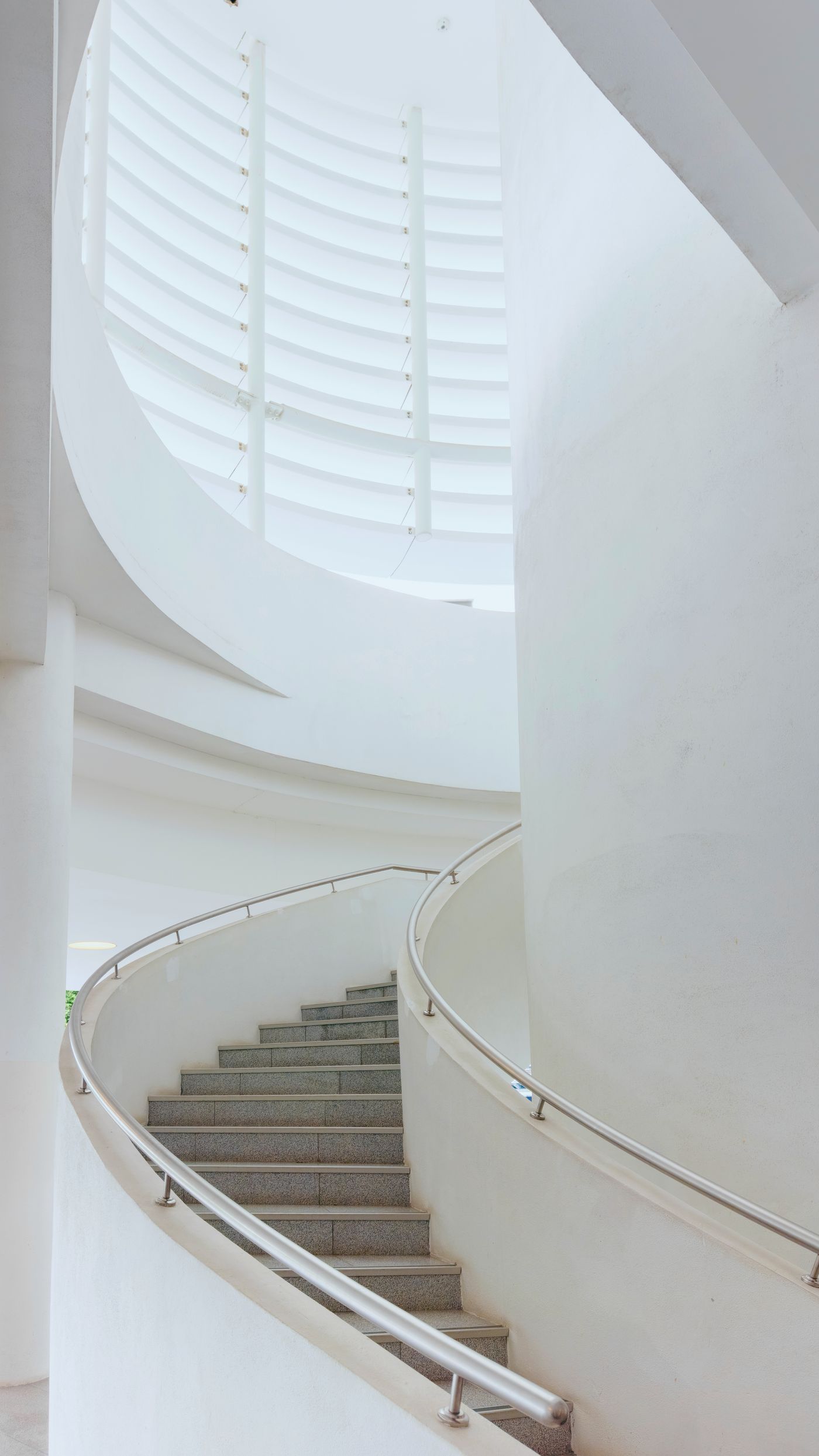 A white curved staircase with a continuous handrail.